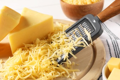 Grated, whole pieces of cheese and grater on table, closeup