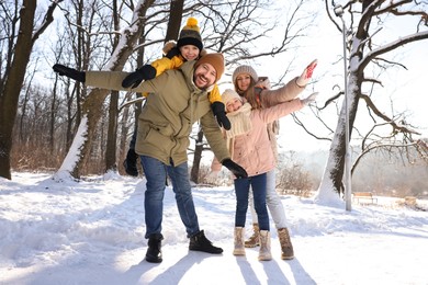 Happy family having fun in sunny snowy forest