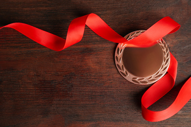 Photo of Bronze medal with ribbon on wooden background, flat lay. Space for design