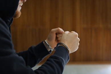 Photo of Man detained in handcuffs indoors, closeup view. Criminal law