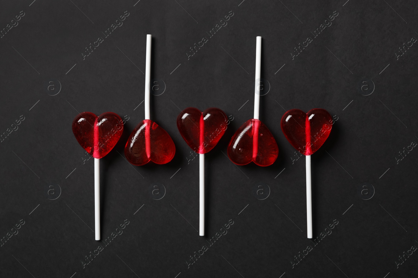 Photo of Sweet heart shaped lollipops on black background, flat lay. Valentine's day celebration