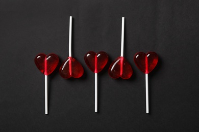 Sweet heart shaped lollipops on black background, flat lay. Valentine's day celebration