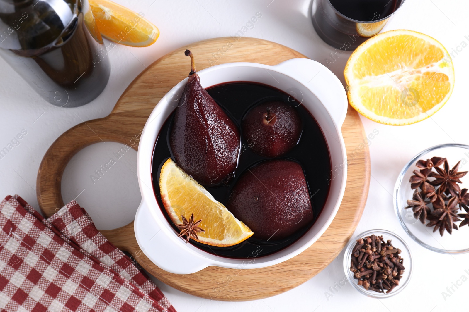 Photo of Tasty red wine poached pears in pot, orange and spices on white table, flat lay