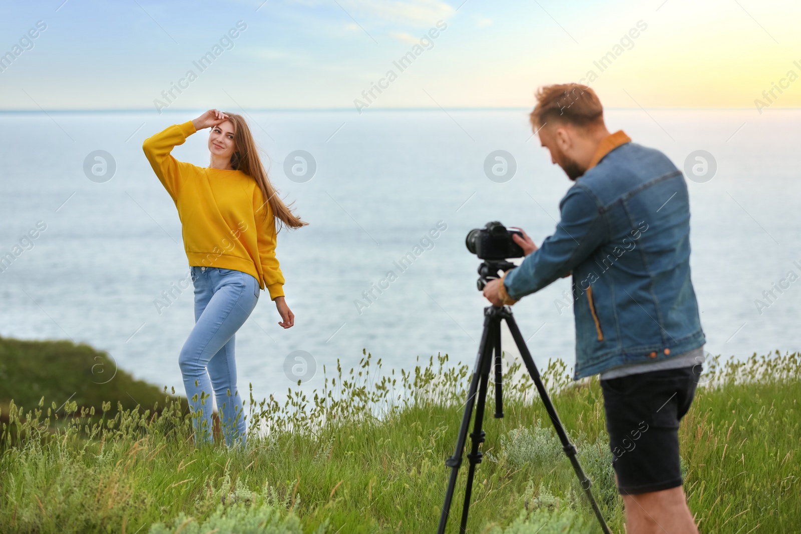 Photo of Male photographer taking picture of young woman with professional camera outdoors