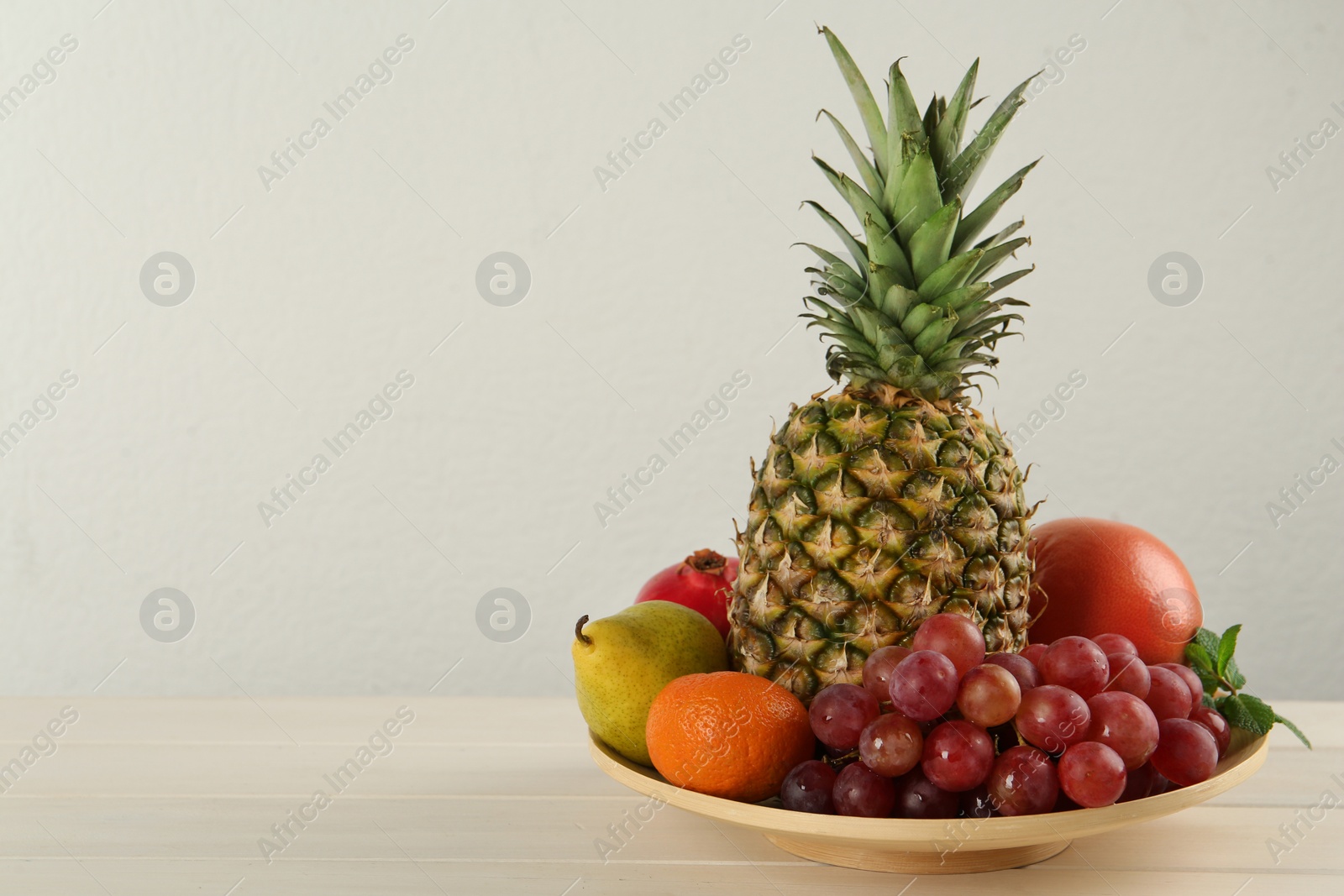 Photo of Fresh ripe fruits on white wooden table, space for text