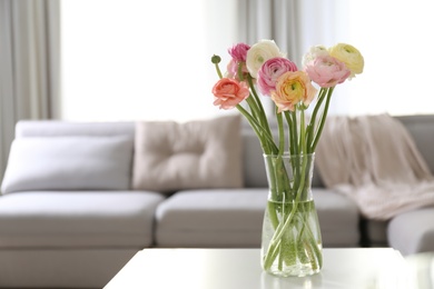 Photo of Beautiful ranunculus flowers on table in living room, space for text
