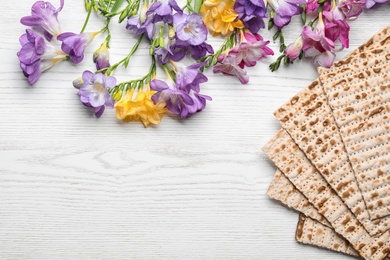 Photo of Flat lay composition of matzo and flowers on wooden background, space for text. Passover (Pesach) Seder