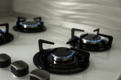 Photo of Gas burners with blue flame on modern stove