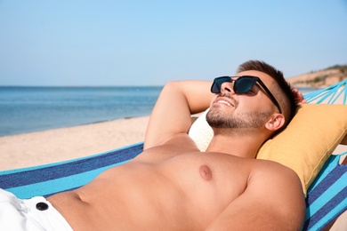 Photo of Young man relaxing in hammock on beach