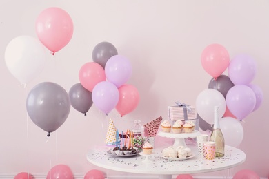 Party treats and items on table in room decorated with balloons