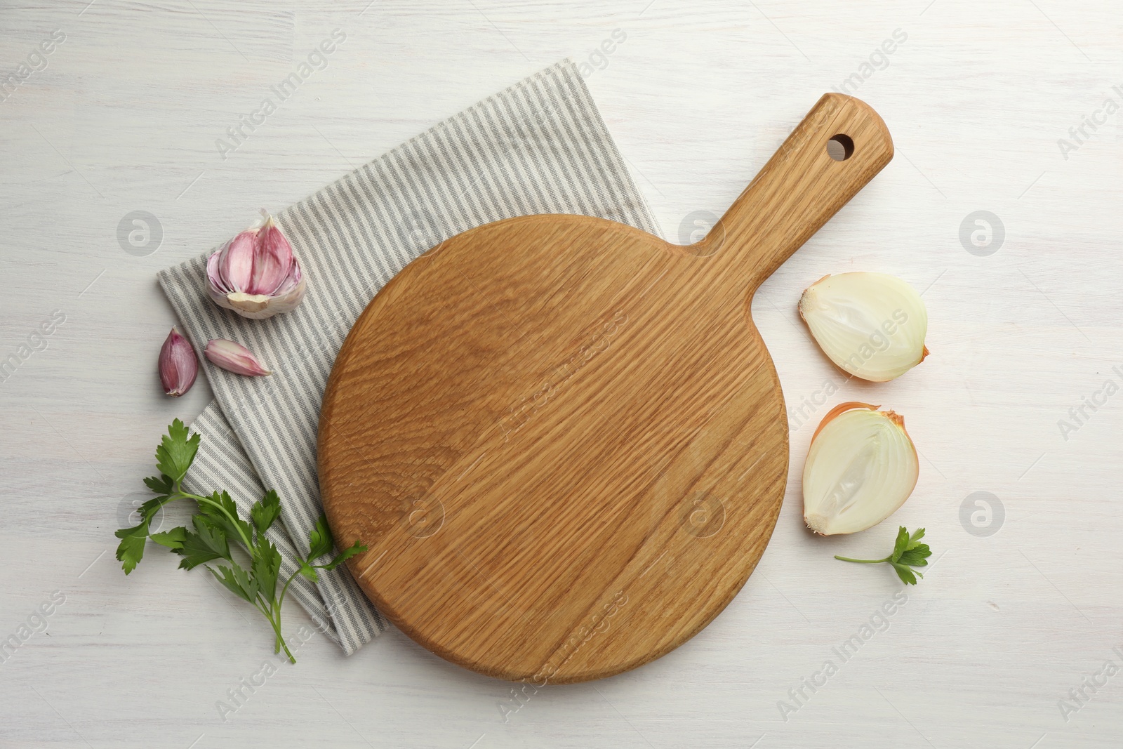 Photo of Cutting board, parsley, garlic and onion on white wooden table, flat lay. Space for text