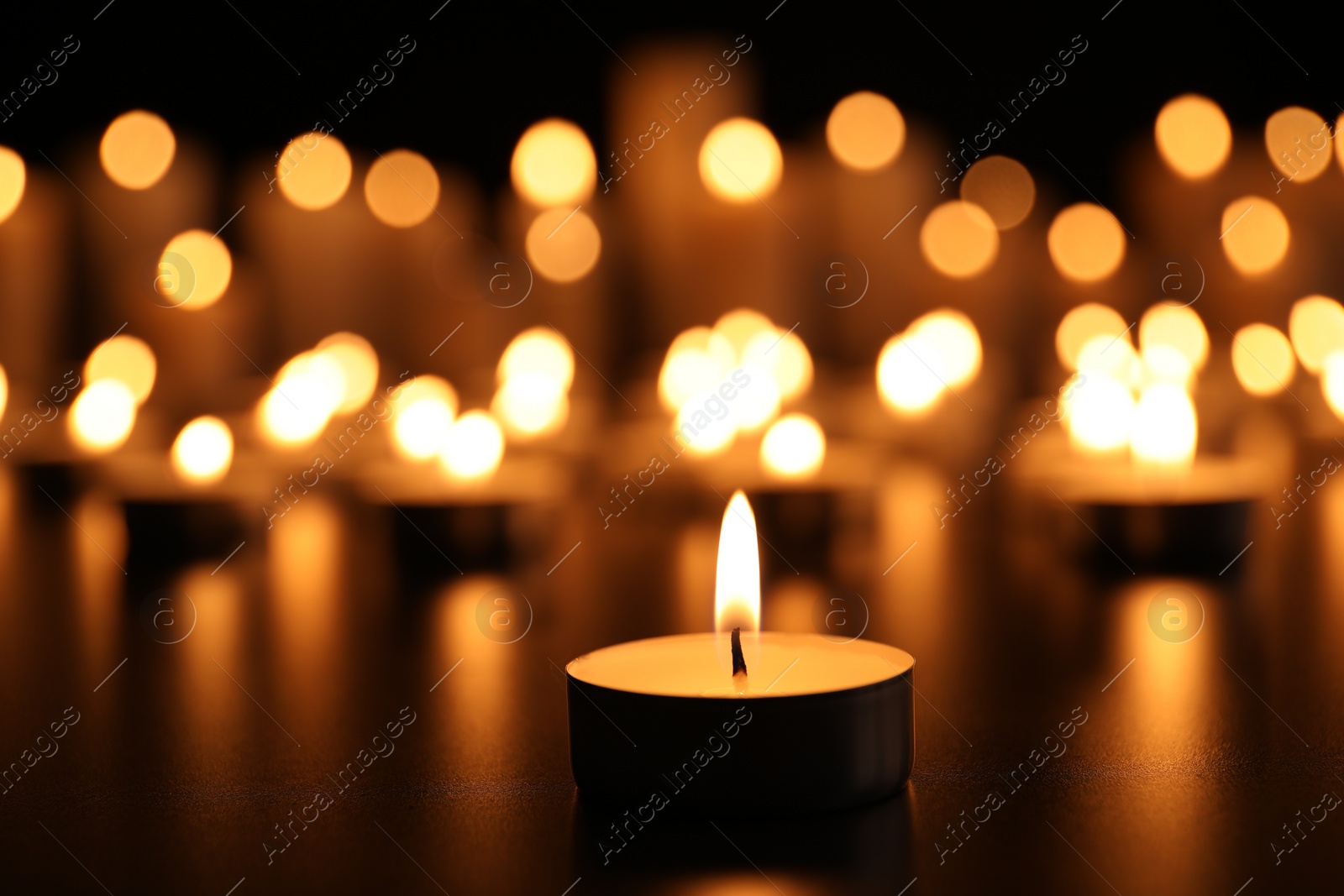 Photo of Burning candle on black table. Memory day