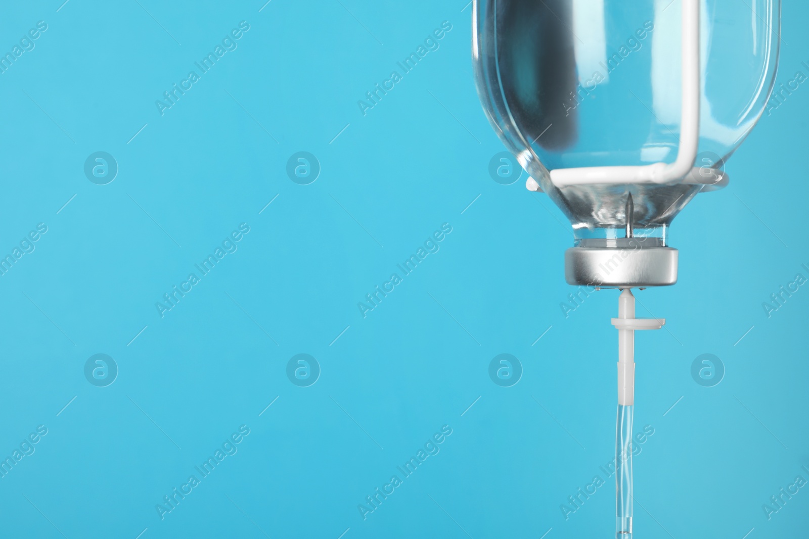 Photo of IV infusion set on light blue background, closeup. Space for text