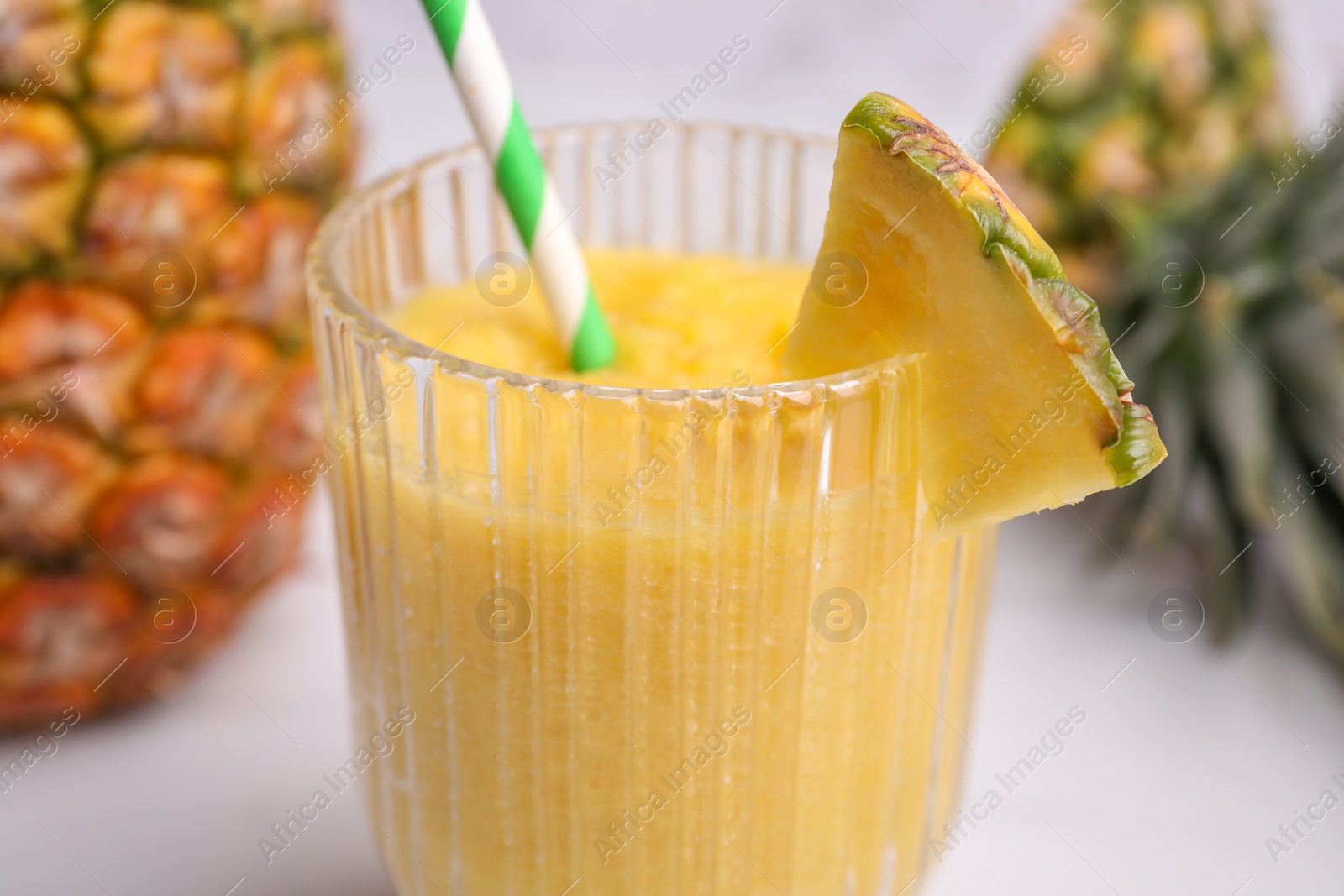 Photo of Tasty pineapple smoothie and cut fruit on light table, closeup