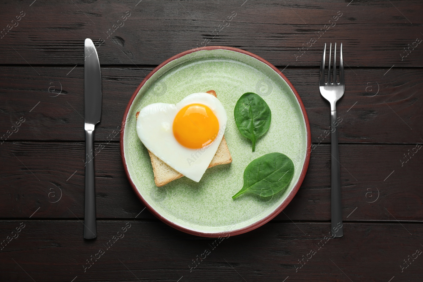 Photo of Tasty breakfast with heart shaped fried egg served on wooden table, flat lay
