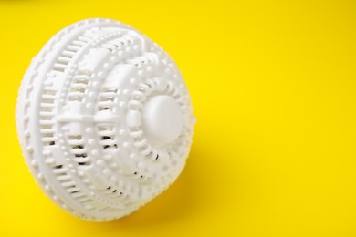 Photo of Laundry dryer ball on yellow background, space for text