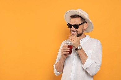 Man drinking delicious juice on orange background, space for text