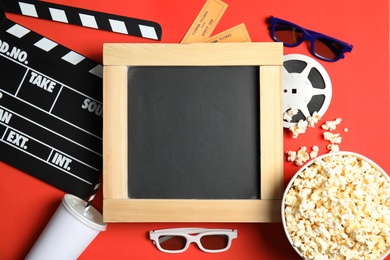 Flat lay composition with blackboard, popcorn and clapper on color background, mockup for design. Watching cinema