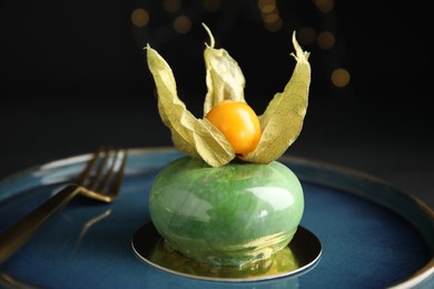 Delicious mousse cake decorated with physalis fruit on black background, closeup