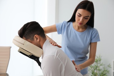 Man receiving massage in modern chair indoors