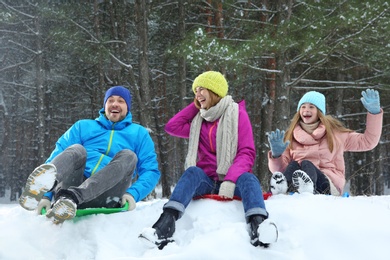 Happy family sledding in forest on snow day