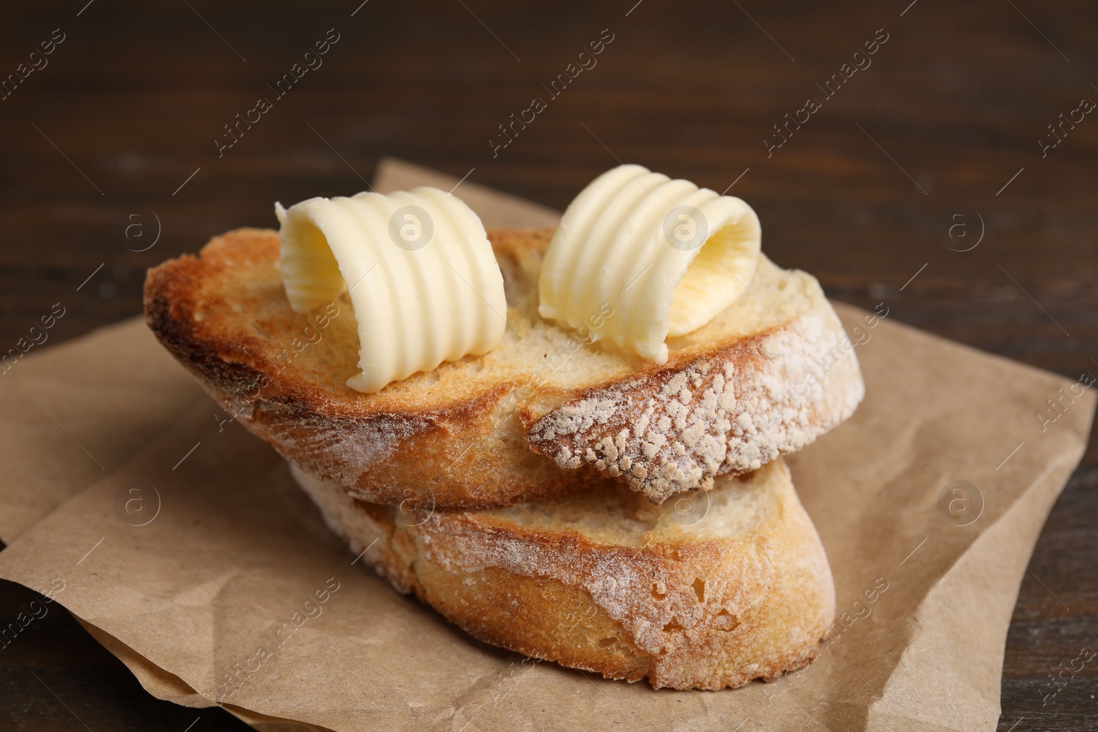 Photo of Tasty butter curls and slices of bread on wooden table, closeup