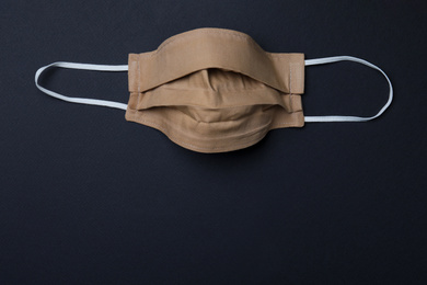 Photo of Homemade protective mask on black background, top view with space for text. Sewing idea