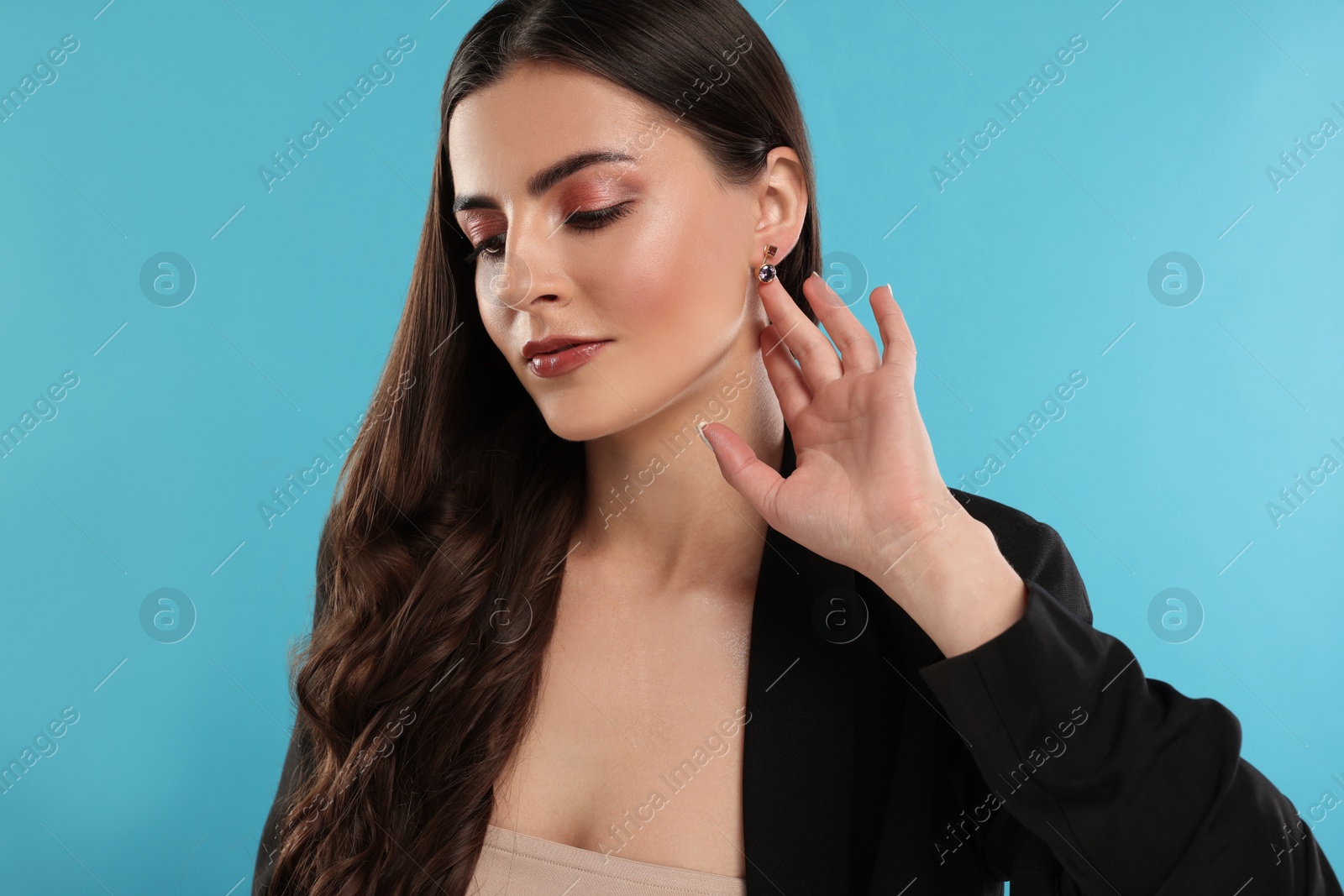 Photo of Beautiful woman with elegant earrings on light blue background