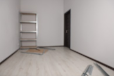 Photo of Blurred view of room with white walls and metal storage shelf