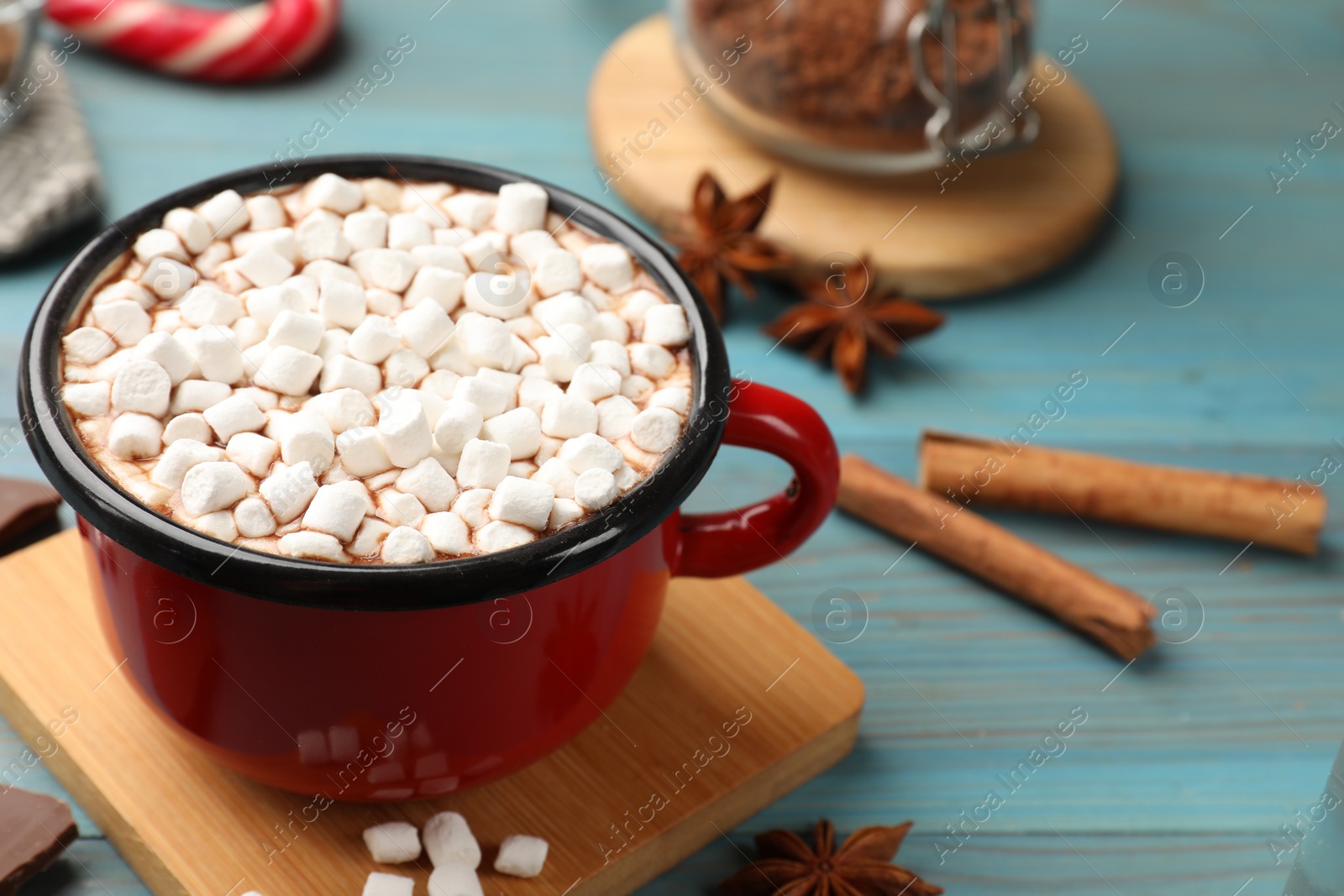 Photo of Tasty hot chocolate with marshmallows on light blue wooden table, closeup