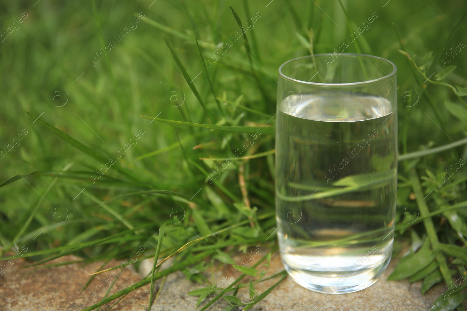 Photo of Pouring fresh water on stone surface outdoors, space for text