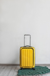 Photo of Bright yellow suitcase and leaf shaped rug indoors