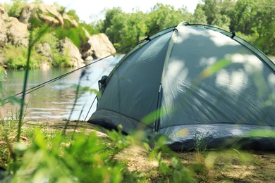 Modern camping tent on riverbank. Space for text