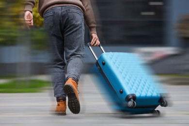 Image of Being late. Man with suitcase running on city street, closeup. Motion blur effect