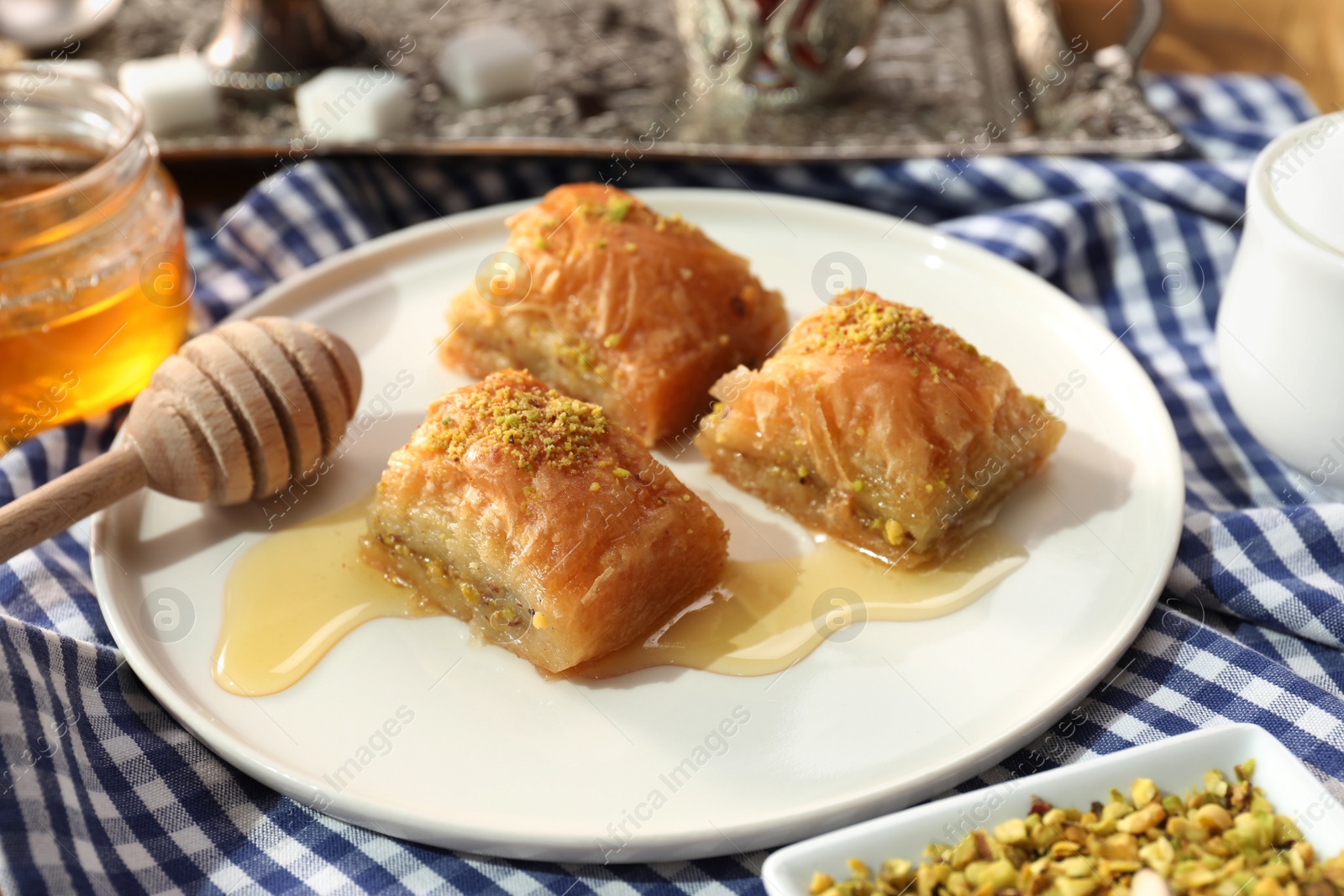 Photo of Delicious sweet baklava with pistachios and honey on table, closeup