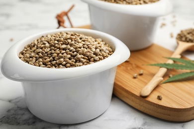 Photo of Organic hemp seeds in bowl on marble table