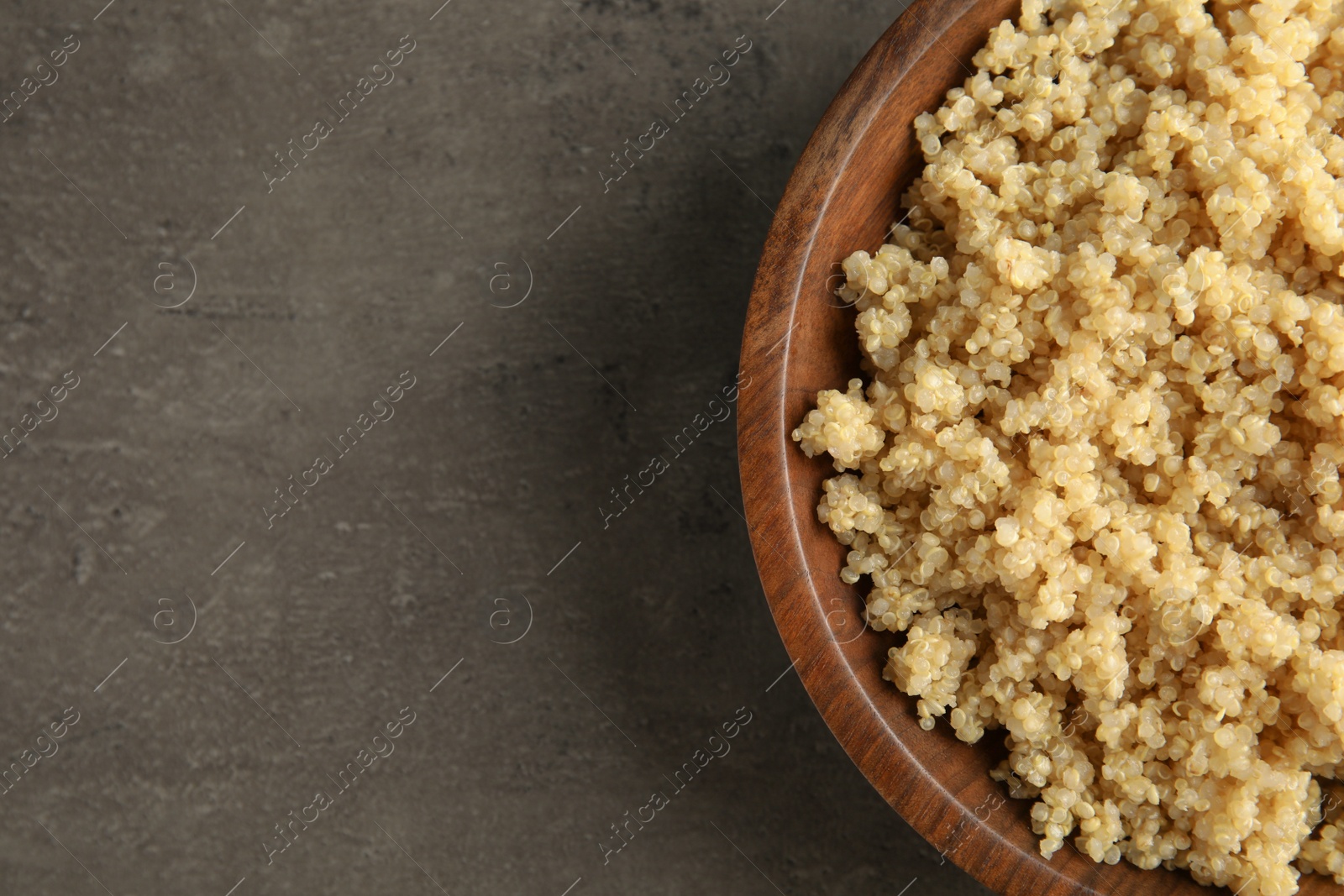 Photo of Cooked delicious quinoa in wooden bowl on table, top view. Space for text