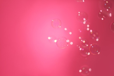 Photo of Beautiful translucent soap bubbles on pink background, space for text