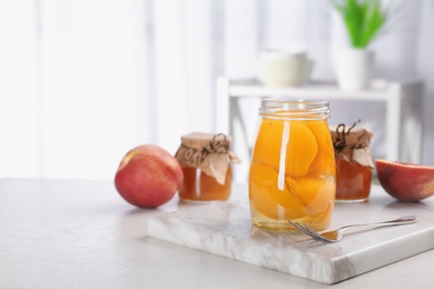 Photo of Glass jar with conserved peach halves on table. Space for text