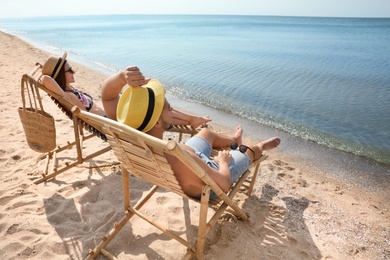 Young couple relaxing in deck chairs on beach