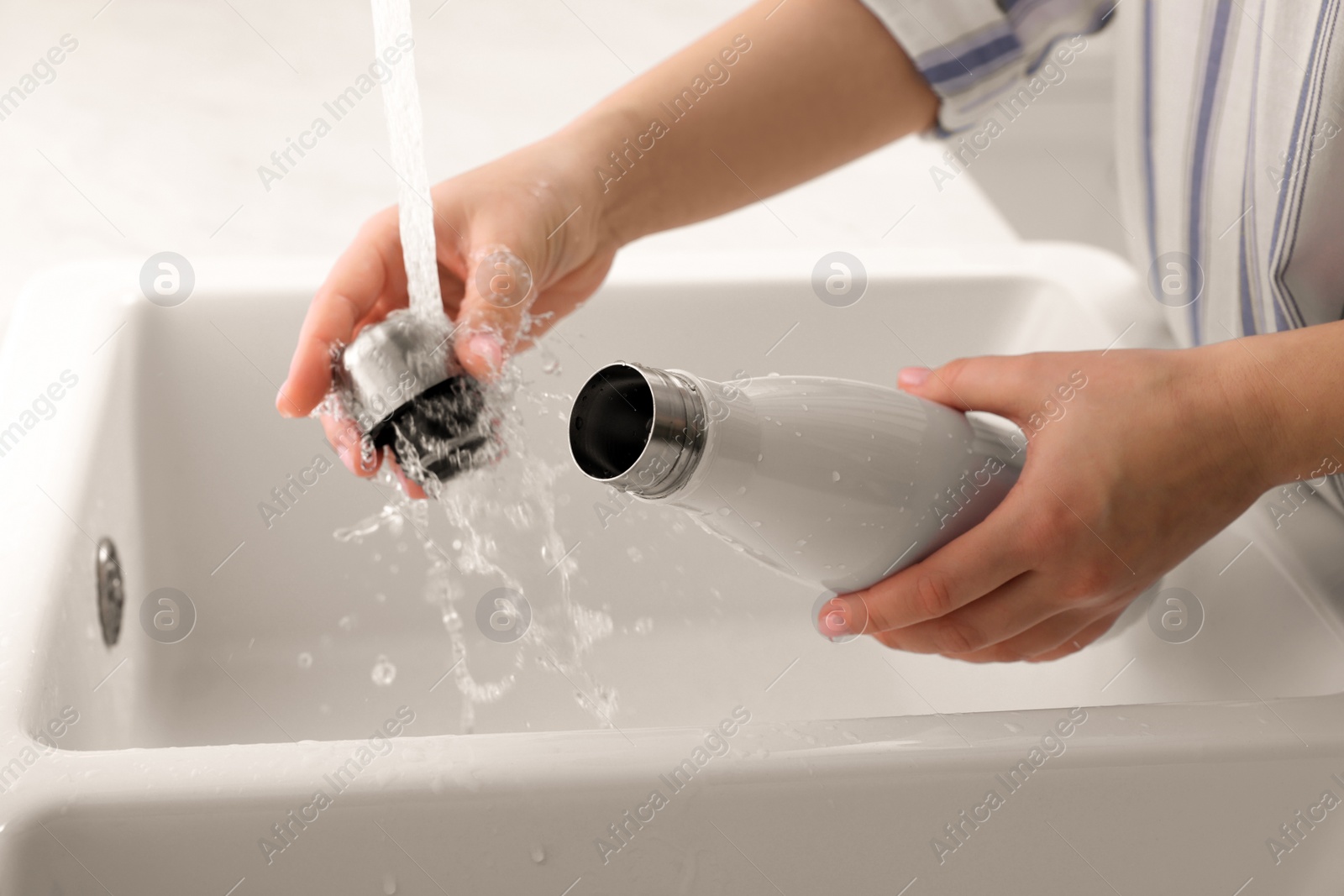 Photo of Woman washing thermo bottle in kitchen, closeup