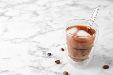 Glass with cold brew coffee and beans on light background