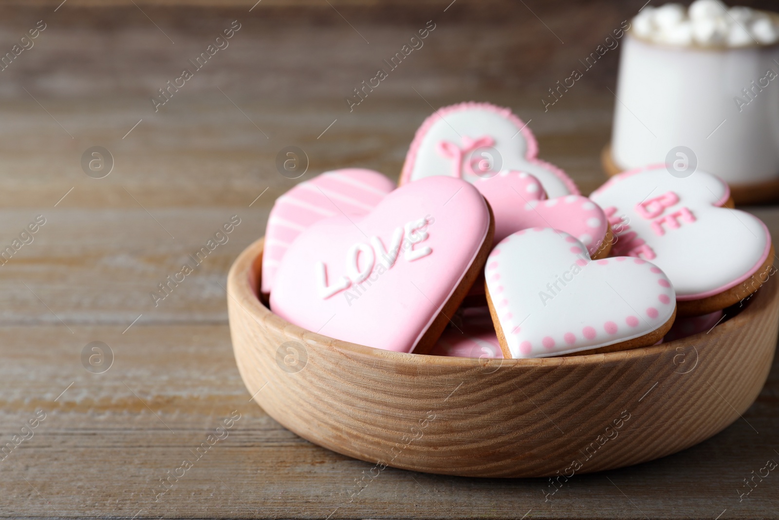 Photo of Valentine's day cookies in bowl on wooden table. Space for text