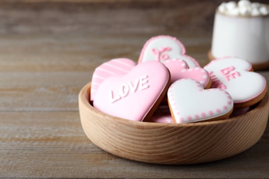 Valentine's day cookies in bowl on wooden table. Space for text