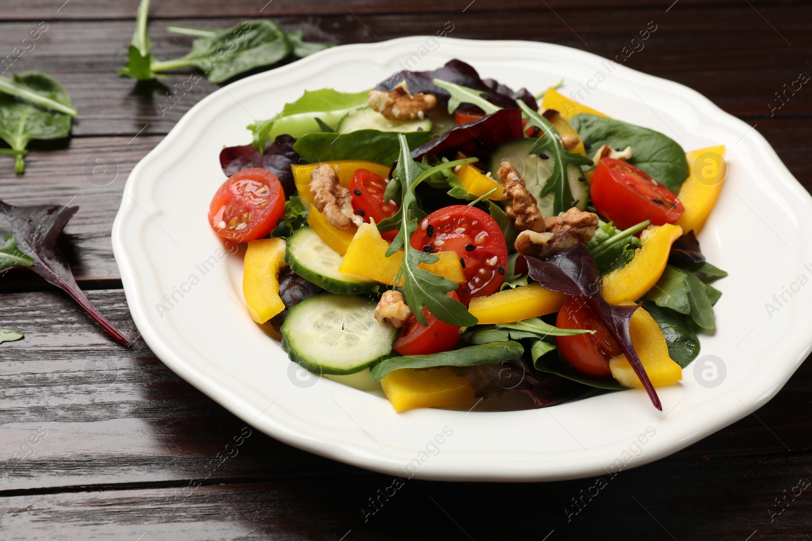 Photo of Tasty fresh vegetarian salad on dark wooden table, closeup