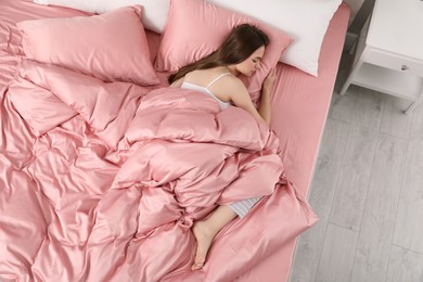 Photo of Young woman sleeping in comfortable bed with silky linens, above view