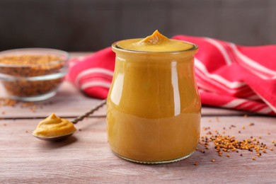 Photo of Tasty mustard sauce in jar on wooden table, closeup