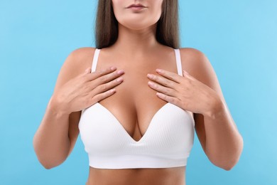 Woman with beautiful breast on light blue background, closeup