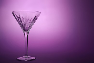 Photo of Elegant empty martini glass on purple background. Space for text