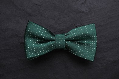 Photo of Stylish green bow tie with polka dot pattern on black table, top view